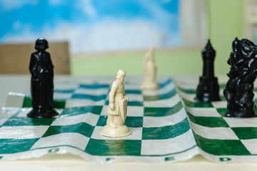 Beautiful old plastic chess pieces stand on a table in a school class. Focus on the white pawn.