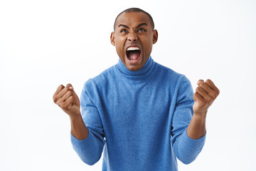 Portrait of excited, extremely happy triumphing african american man celebrating goal, watching sports game football, yelling from cheer, rejoicing victory, standing white background