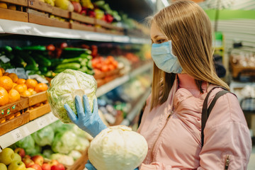 Young girl in medical masks makes purchases in a supermarket in search of food.