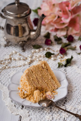Sweet homemade layered honey cake on a white plate with coffee.