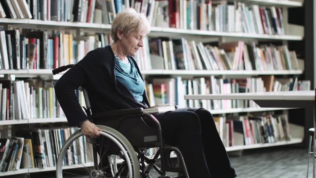 Disabled Senior adult female in wheelchair in library