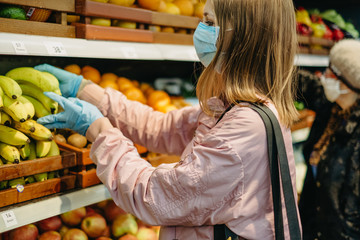 Young girl in medical masks makes purchases in a supermarket in search of food.