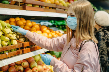 Young girl in medical masks makes purchases in a supermarket in search of food.