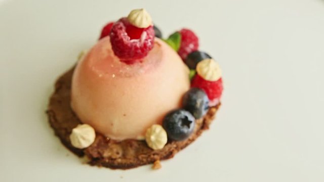 closeup focus in at dessert finely decorated with berries rotates on plate