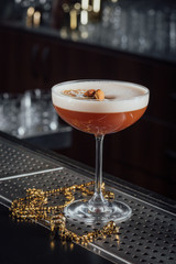 Alcohol coctail drink on the table in bar with gold beads