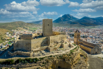 Fototapeta na wymiar Aerial view of medieval Alcaudete castle in Andalusia Spain with donjon, high stone walls and loopholes next to the town church