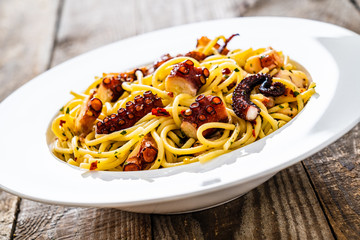 Spaghetti with fried octopus on wooden table