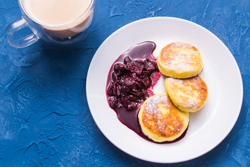 Breakfast and delicious concept - Pancakes from cottage cheese with jam, blue background, top view