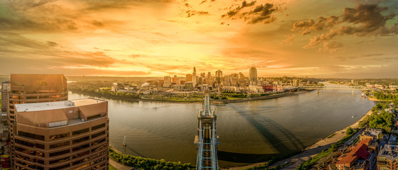 Aerial view Dreamy orange sunset sky over Cincinnati with the Roebling bridge stretching over the Ohio river 