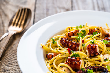 Spaghetti with fried octopus on wooden table