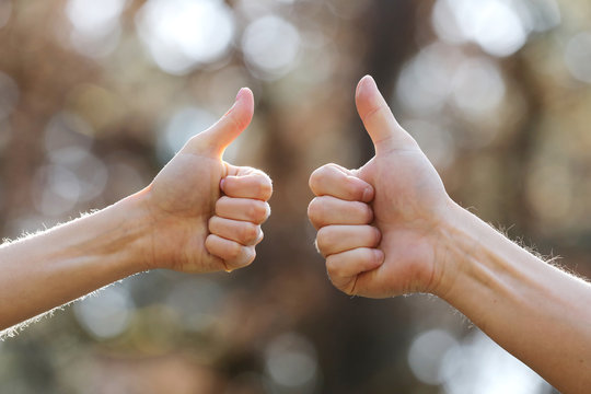 Male And Female Hands Showing Thumbs Up Outdoor. Hands Show Ok On Natural Background. Selective Focus.