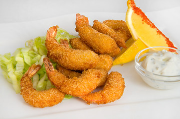 Breaded king prawns with thinly sliced fresh cabbage with lemon slices in red pepper and milk sauce