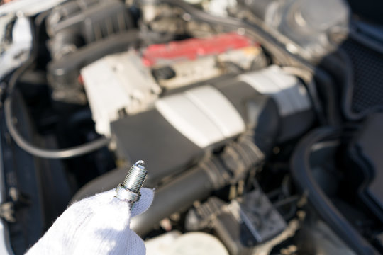 Mechanic hold new iridium spark plug with small electrode for good and high precision spark in difficult condition, high boost or lean air fuel ratio. This image for use to automotive part or service.