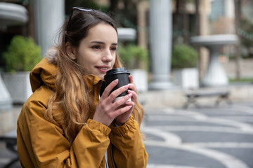 Photo of young tourist girl drinking coffee on streets of Baku. Moody photos of teenager girl visiting city