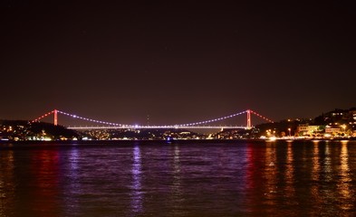 Istanbul Bosporus Bridge with colourful lights and its reflections on sea during night
