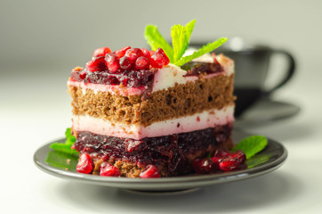 Colorful multi-layered cream chocolate cake with cherry jam and pomegranate