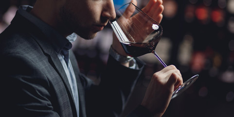 Winemaker sommelier smelling red wine aroma in glass