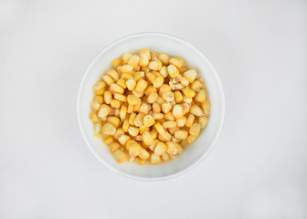 Delicious and fresh yellow sweet corn seed gathered in a white cup over a white background