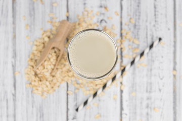 Old wooden table with fresh Oat Milk (close-up shot; selective focus)