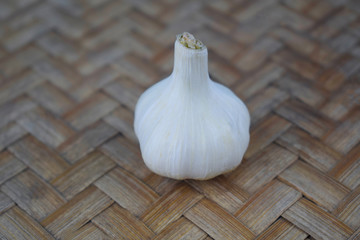 Portrait of a single garlic on top of a wooden colored carpet background
