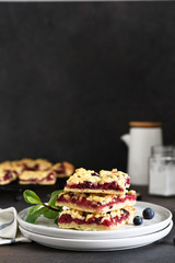 Tasty grated pie with cherries and blueberries on a dark background. Horizontal focus.