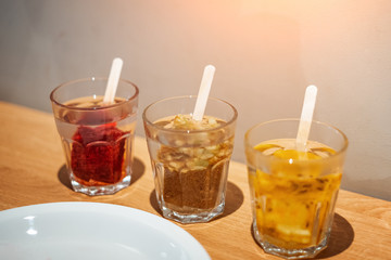 Three fruit drinks in glass glasses on a wooden table.