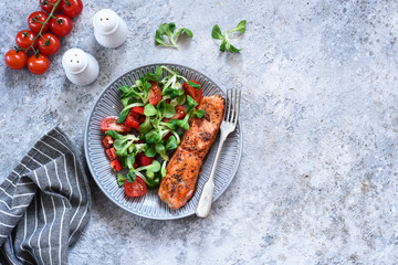 Grilled salmon slice and salad with tomatoes on the kitchen table. Menu for the restaurant.