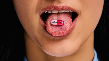 Closeup make up lips and a red-pink tablet on the female tongue. Medical concept