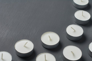 Many circle candles in metal holder on dark concrete surface