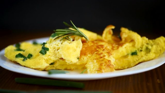 hot fried omelet with chopped green onions in a plate on a wooden table