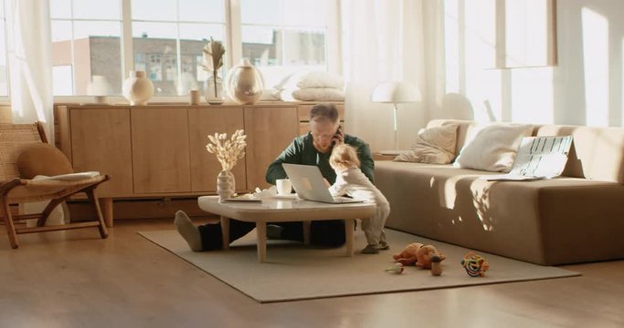 Father working from home, having a work phone call, while feeding his daughter. Stay home, quarantine remote work. Shot on RED Dragon