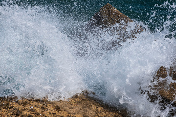 Waves in sea Splashing Waves. Danger sea wave crashing on rock coast with spray and foam before storm. Beautiful sea waves with foam of blue and turquoise color.