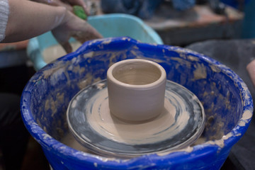 Clay cup stands on a potter's wheel. Pottery hobby. Handcrafted earthenware