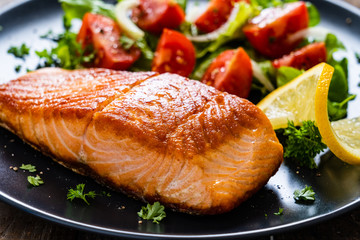 Fried salmon steaks with vegetables on wooden table