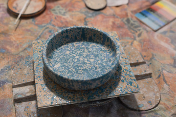 Blue clay plate on the table. Painted plate earthenware standing on table in pottery workshop