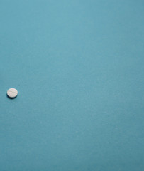 Isolated white pill health medication close-up on blue background