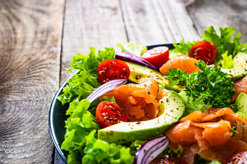 Salmon salad - smoked salmon and vegetables on wooden background