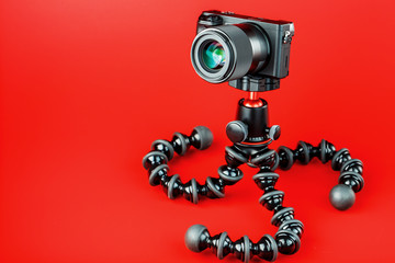 Professional camera on a tripod, on a red background. Record videos and photos for your blog, reportage