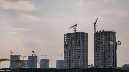 Fototapeta na wymiar construction cranes, houses in the distance. city landscape