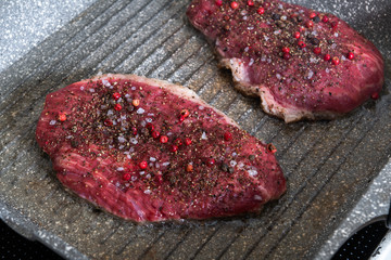 Raw fresh marbled meat on a pan with salt and pepper