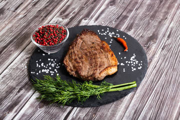 Grilled beef steak ribeye with salt and pepper on dark wooden background top view