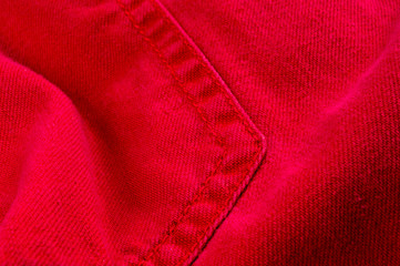 clothing items stonewashed red cotton fabric texture with seams, clasps, buttons and rivets, macro