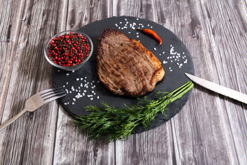 Grilled beef steak ribeye with salt and pepper on dark wooden background top view
