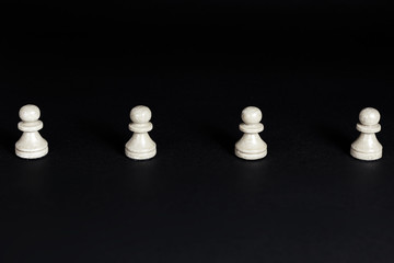 White pawns in line on dark background. Pawns parade. Social distancing and communication concept...