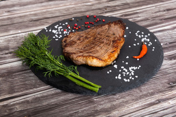 Grilled beef steak ribeye with salt and pepper on dark wooden background top view