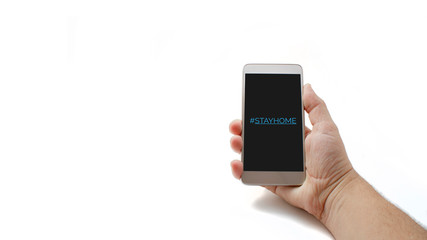 Hashtag stay home! The inscription on the smartphone screen. Male hand holds a phone isolated on a white background. The recommendation is quarantined at home to prevent coronovirus covid 19.
