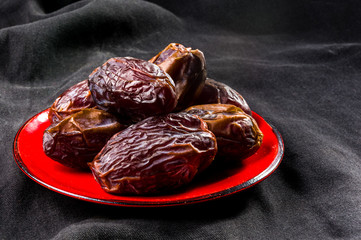 Big luxury dried date fruit in bowls on the dark surface, kurma ramadan kareem concept, close up.