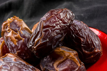 Big luxury dried date fruit in bowls on the dark surface, kurma ramadan kareem concept, close up.