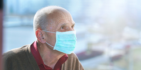 man in protective face mask anti virus looks at city street through window