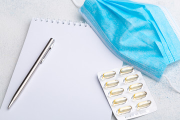 Medical face shield, pills, pen and paper on white background. The concept of protecting health...